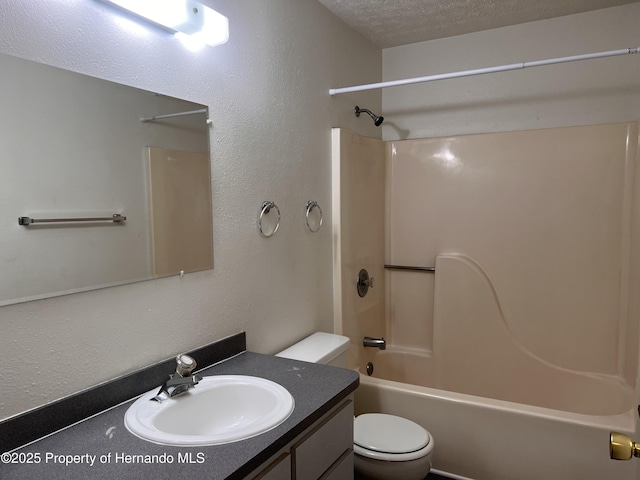 full bathroom featuring vanity, bathing tub / shower combination, toilet, and a textured ceiling