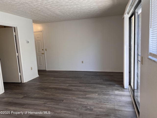 empty room with dark hardwood / wood-style floors and a textured ceiling