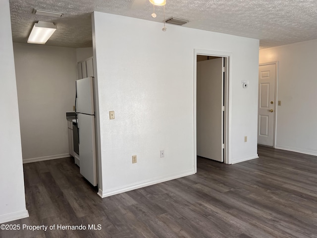 unfurnished room featuring dark wood-type flooring and a textured ceiling