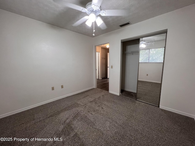 unfurnished bedroom featuring dark carpet, a textured ceiling, ceiling fan, and a closet