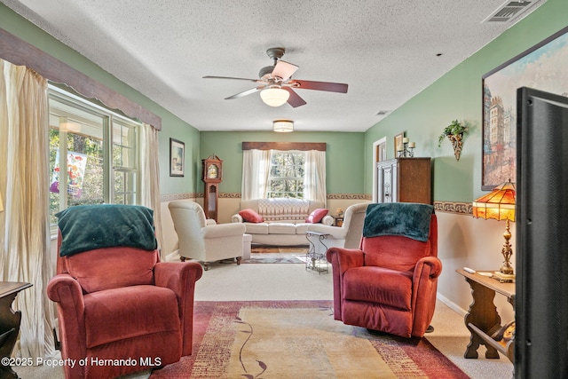 living room with a textured ceiling, ceiling fan, and carpet floors