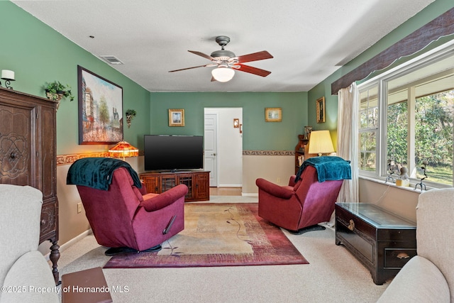 living room with ceiling fan, light carpet, and a textured ceiling