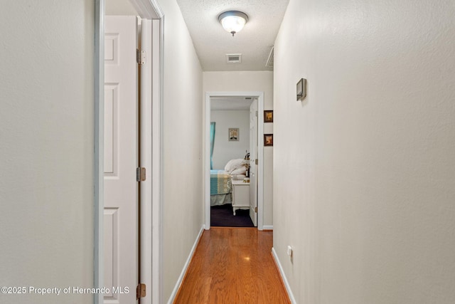 hallway with a textured ceiling and hardwood / wood-style flooring