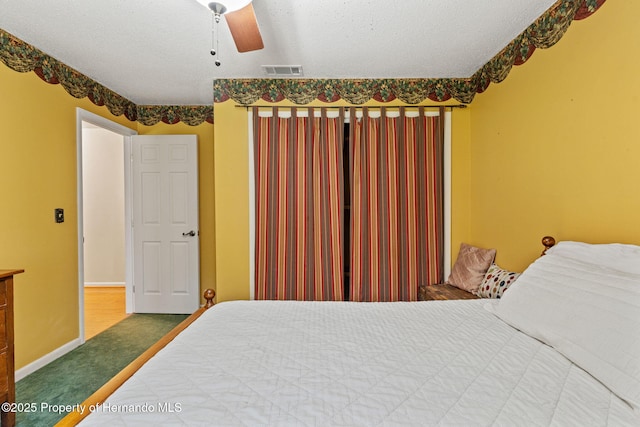 carpeted bedroom featuring ceiling fan and a textured ceiling