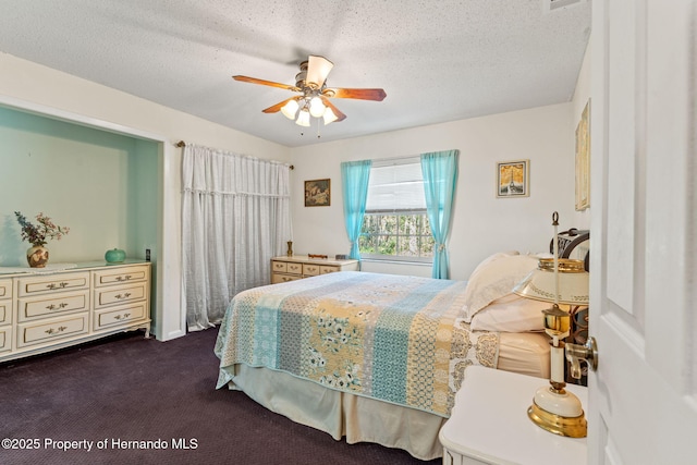 bedroom featuring a textured ceiling, ceiling fan, and dark colored carpet