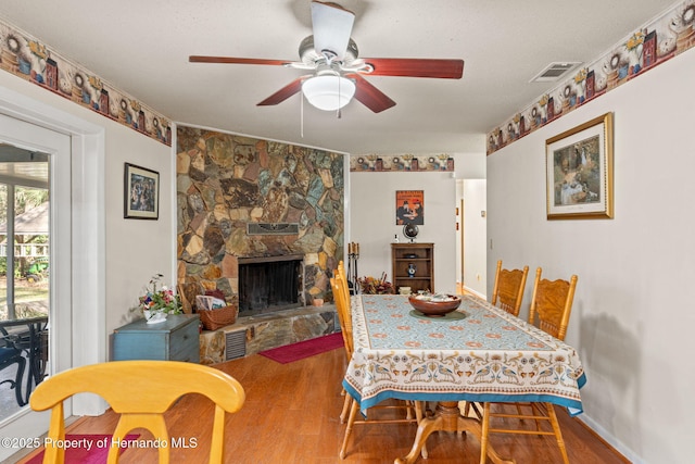 dining area featuring a fireplace, a textured ceiling, ceiling fan, and wood-type flooring