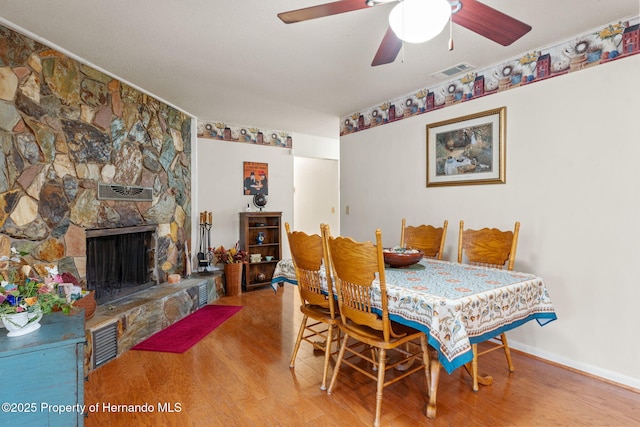 dining room featuring wood-type flooring, a fireplace, and ceiling fan