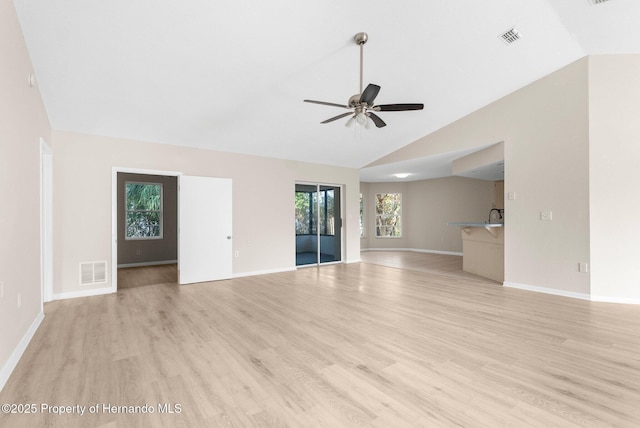 unfurnished living room with light wood-type flooring, vaulted ceiling, ceiling fan, and sink