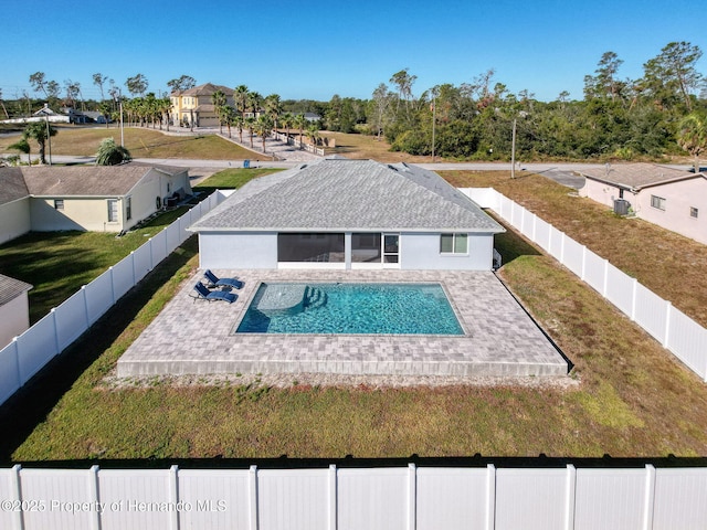 rear view of property featuring a yard, a patio, a fenced in pool, and central AC