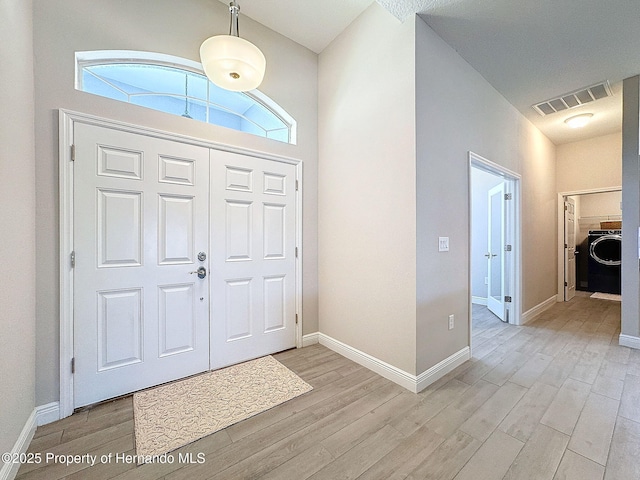 foyer entrance featuring washer / dryer, plenty of natural light, and light hardwood / wood-style flooring