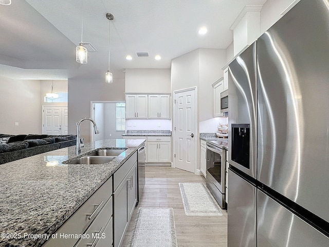 kitchen with dark stone counters, sink, decorative light fixtures, white cabinetry, and stainless steel appliances