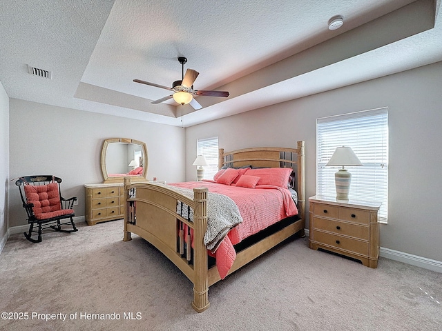 bedroom with ceiling fan, a raised ceiling, light colored carpet, and a textured ceiling