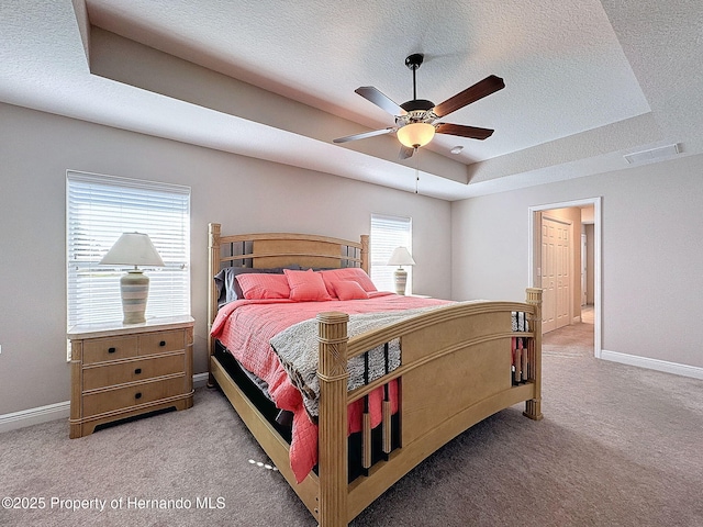 carpeted bedroom with a raised ceiling, ceiling fan, and a textured ceiling