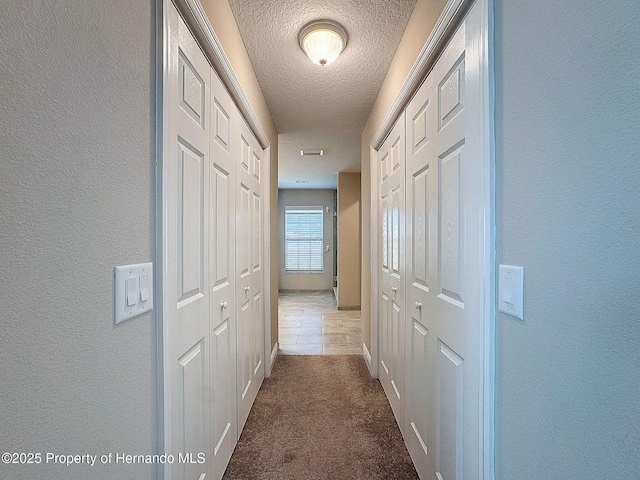 hallway with carpet and a textured ceiling