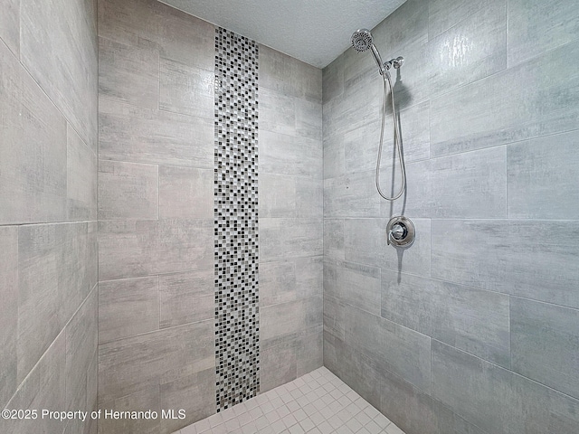 bathroom with a tile shower and a textured ceiling