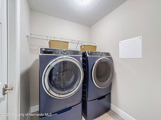 washroom with a textured ceiling and washing machine and clothes dryer