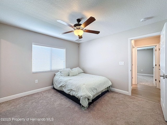 carpeted bedroom with ceiling fan and a textured ceiling