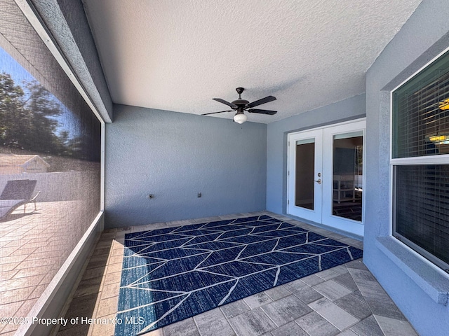 unfurnished sunroom with ceiling fan and french doors