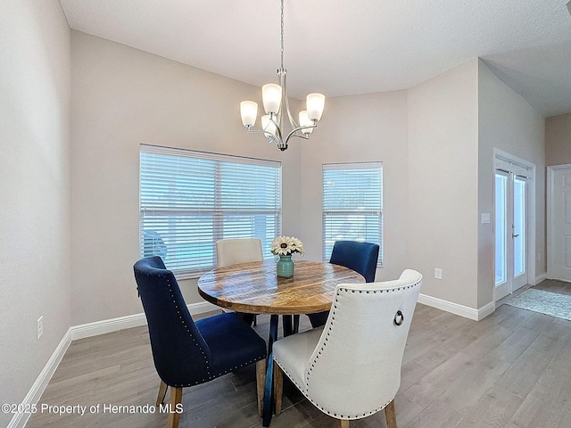 dining space with light wood-type flooring and a chandelier