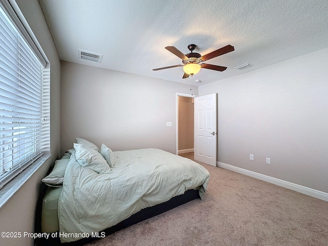 bedroom featuring carpet flooring, ceiling fan, and a textured ceiling