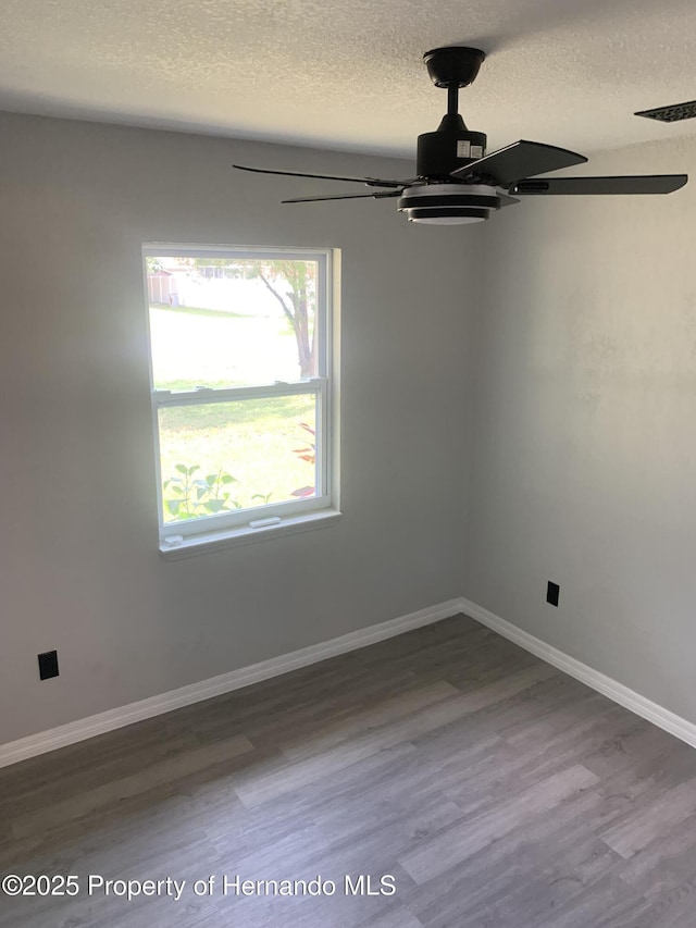 empty room featuring wood-type flooring, a textured ceiling, and a healthy amount of sunlight