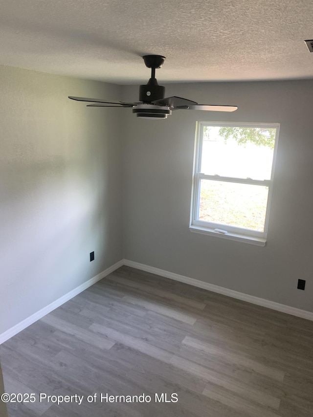 empty room featuring a textured ceiling, hardwood / wood-style flooring, and ceiling fan