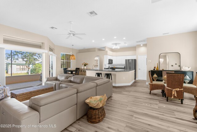 living room with light wood-type flooring and ceiling fan