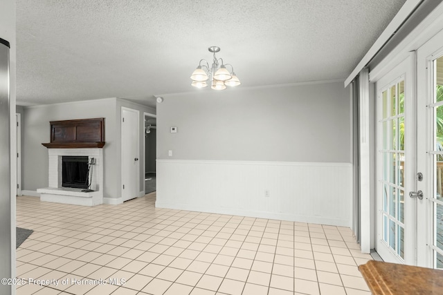 interior space featuring a brick fireplace, light tile patterned floors, a notable chandelier, and a textured ceiling