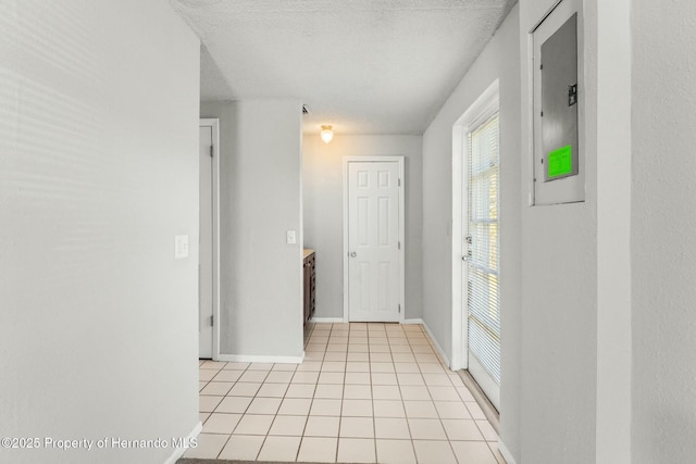 hall with light tile patterned flooring, electric panel, and a textured ceiling