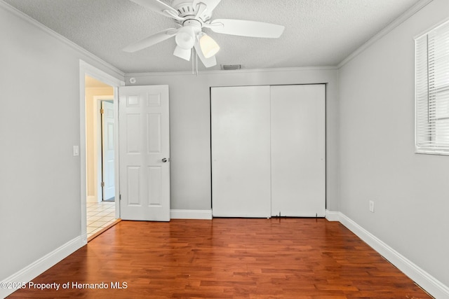 unfurnished bedroom with crown molding, hardwood / wood-style flooring, a closet, and a textured ceiling