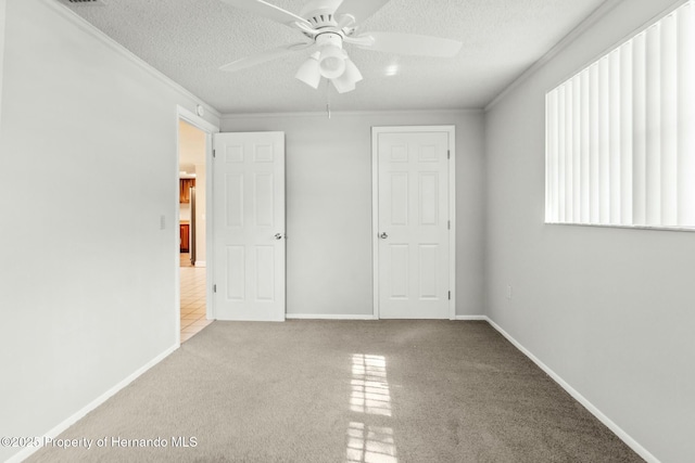 unfurnished bedroom with crown molding, light colored carpet, ceiling fan, and a textured ceiling