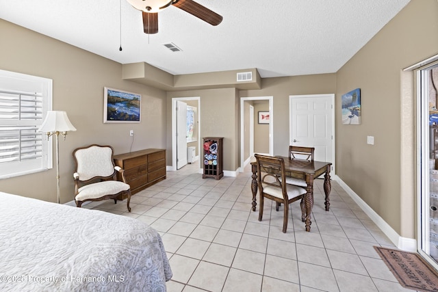 bedroom with ceiling fan, ensuite bathroom, light tile patterned floors, and a textured ceiling