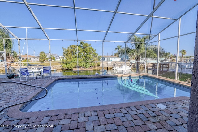 view of pool with glass enclosure, a patio area, and a water view