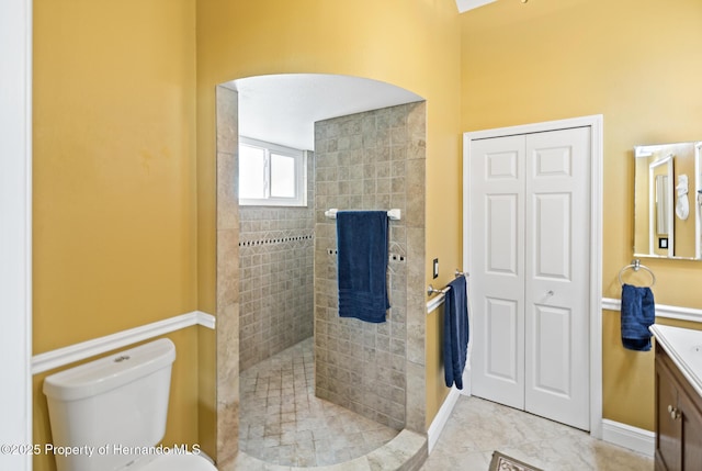 bathroom featuring tiled shower, toilet, tile patterned floors, and vanity