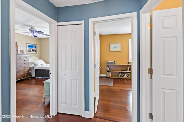 hall with a textured ceiling and dark hardwood / wood-style floors