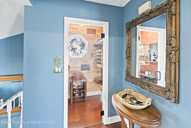 hall with hardwood / wood-style floors and a textured ceiling