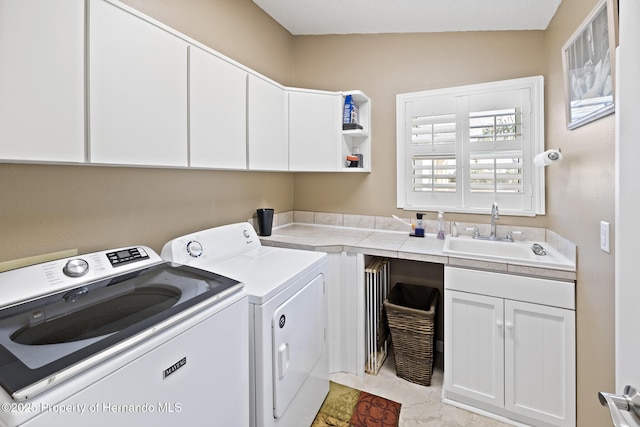 clothes washing area featuring sink, cabinets, and washing machine and dryer