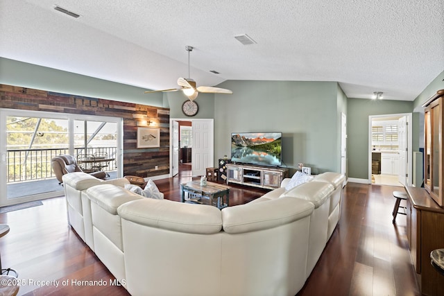 living room with wood walls, a healthy amount of sunlight, dark wood-type flooring, and lofted ceiling