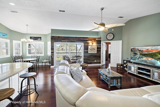 living room with ceiling fan with notable chandelier, a textured ceiling, lofted ceiling, dark wood-type flooring, and wood walls