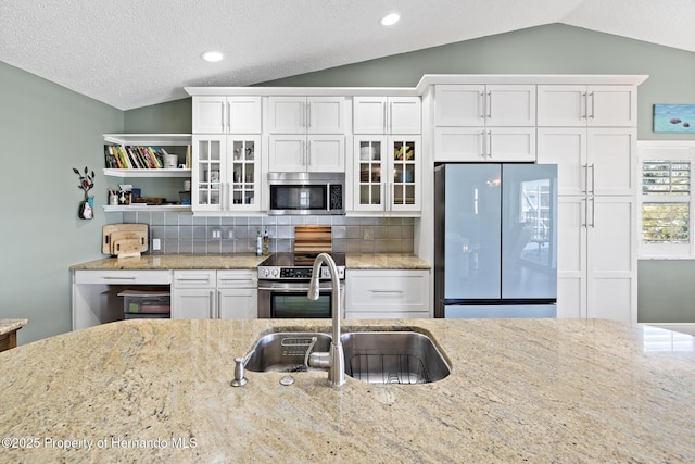 kitchen featuring sink, backsplash, vaulted ceiling, and appliances with stainless steel finishes