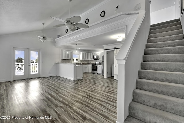 unfurnished living room with ceiling fan, crown molding, a barn door, and dark hardwood / wood-style floors