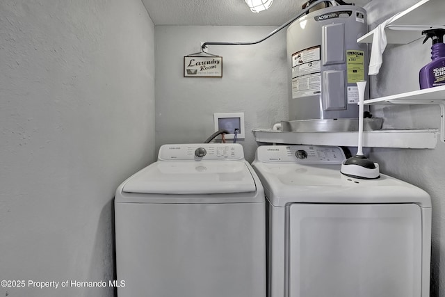 laundry area featuring washing machine and dryer, a textured ceiling, and electric water heater