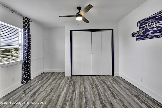 unfurnished bedroom with ceiling fan, a closet, and hardwood / wood-style flooring