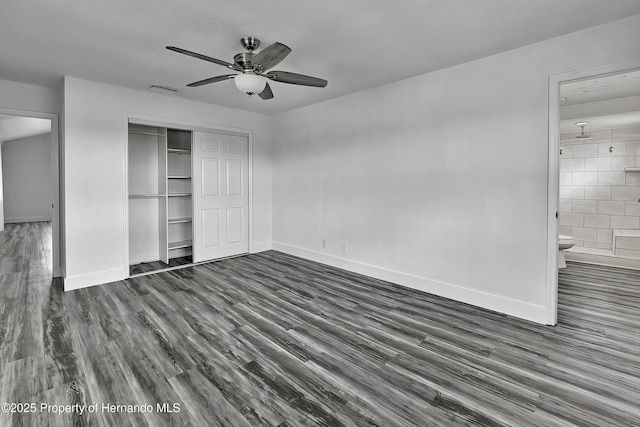 unfurnished bedroom featuring ensuite bath, a closet, ceiling fan, and dark wood-type flooring