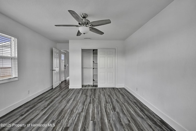 unfurnished bedroom with ceiling fan, dark wood-type flooring, and a closet