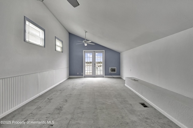 carpeted spare room with vaulted ceiling, an AC wall unit, ceiling fan, and french doors