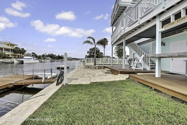 view of dock with a patio, a yard, and a water view