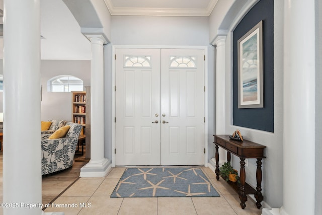 tiled foyer with crown molding and ornate columns