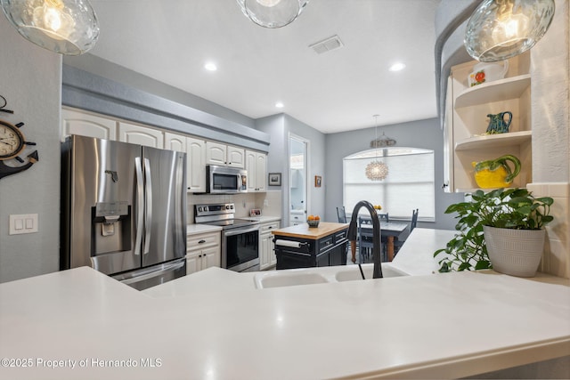 kitchen featuring stainless steel appliances, sink, white cabinetry, tasteful backsplash, and hanging light fixtures