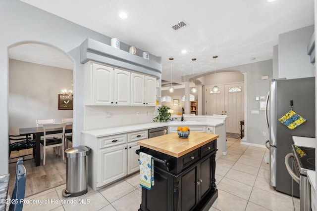 kitchen with kitchen peninsula, a center island, pendant lighting, and white cabinetry